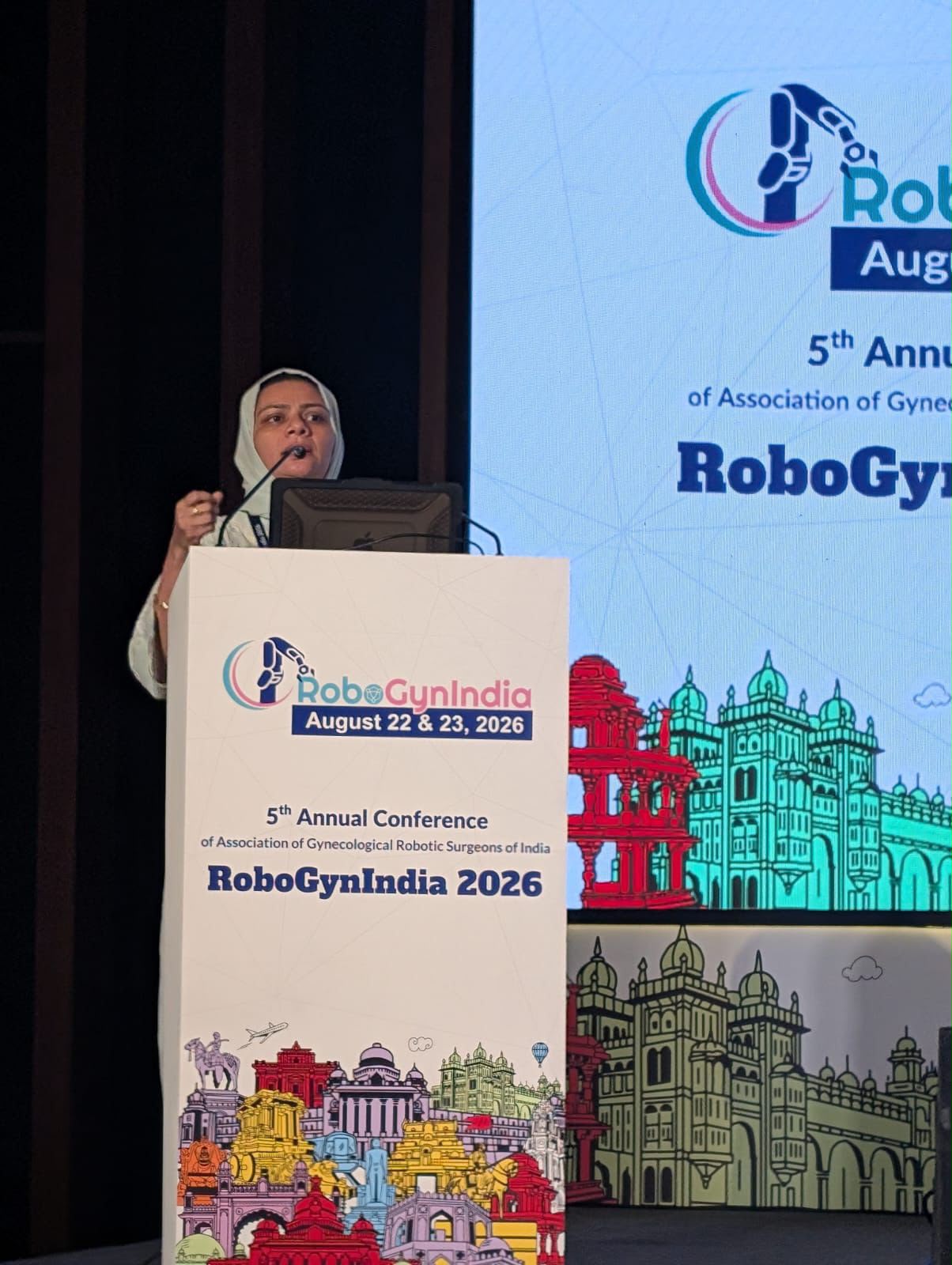 Dr. Mariam Anjum speaking at the podium at RoboGynIndia 2026, 5th Annual Conference of the Association of Gynecological Robotic Surgeons of India